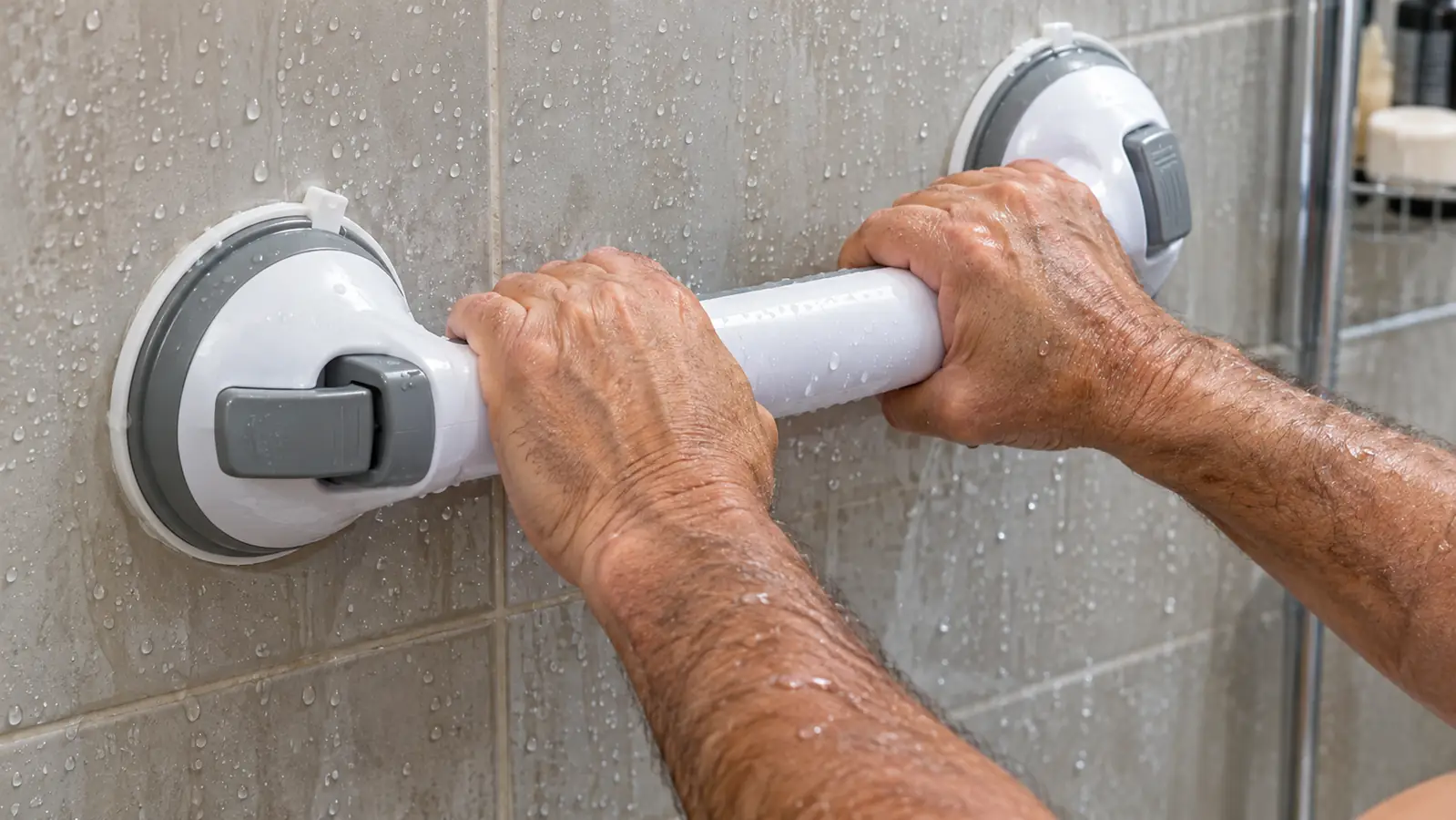 Hand gripping a suction grab bar inside a shower for support