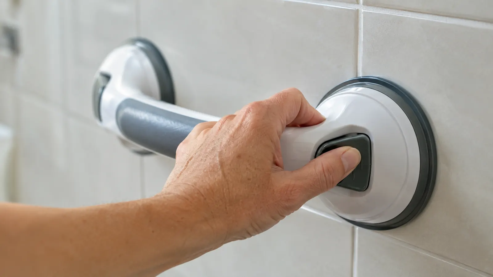 A hand pressing the release lever on a suction grab bar to check it before use